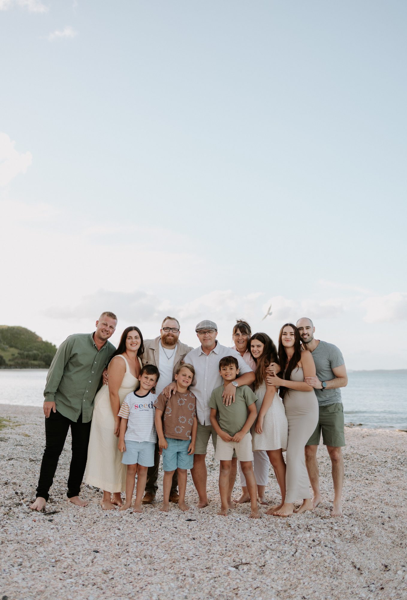Extended family group of ten smiling together on a beach